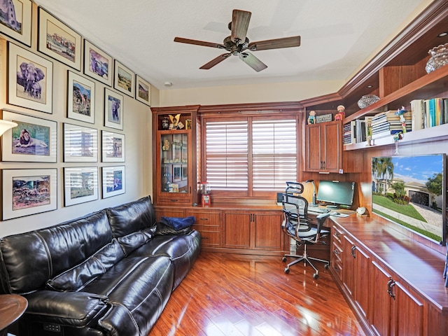 office featuring ceiling fan, built in desk, and light hardwood / wood-style flooring