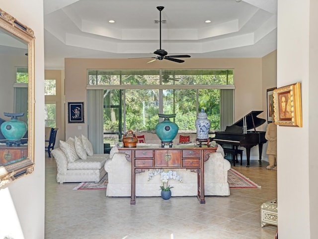 tiled living room featuring a tray ceiling and ceiling fan