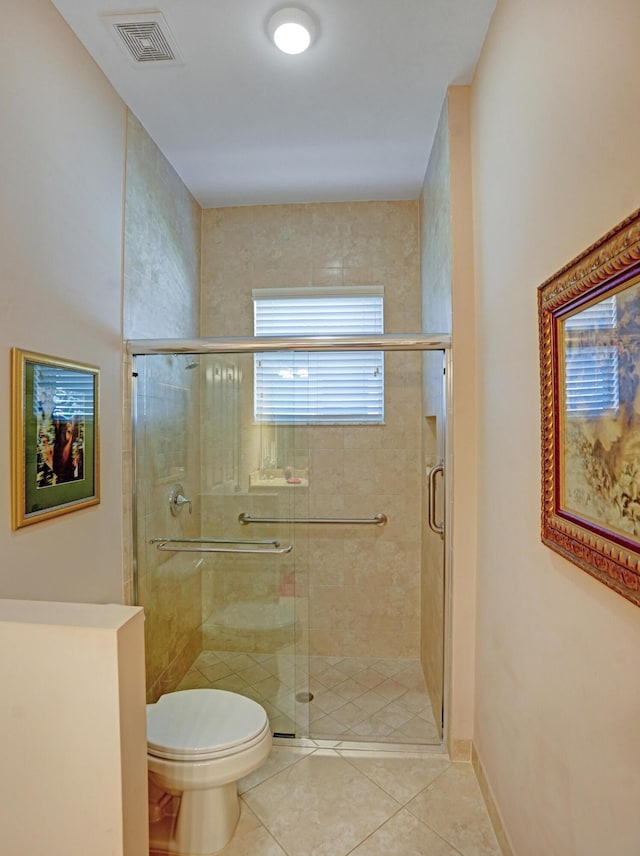 bathroom featuring tile patterned flooring, toilet, and a shower with door