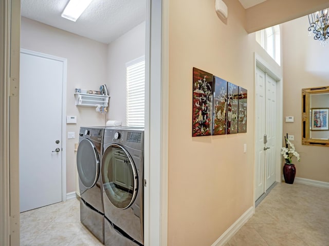 clothes washing area featuring a textured ceiling, washer and clothes dryer, a notable chandelier, and light tile patterned flooring