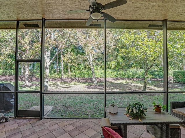 unfurnished sunroom featuring ceiling fan and plenty of natural light