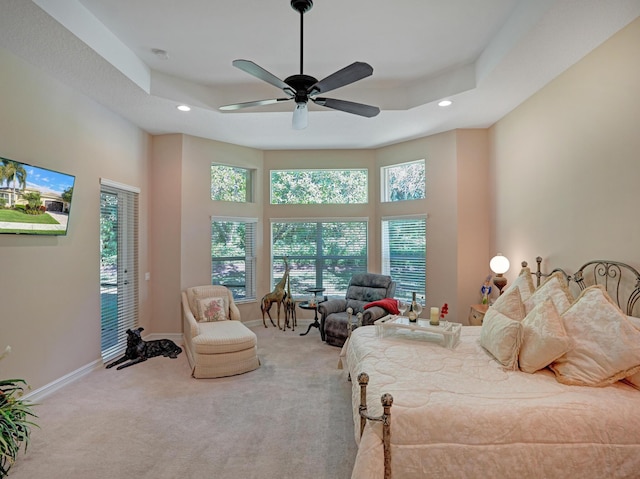 carpeted bedroom with a raised ceiling, ceiling fan, and a high ceiling