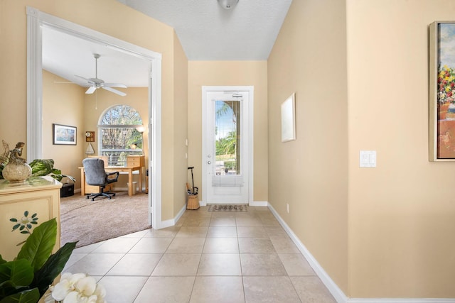 foyer entrance featuring ceiling fan, light tile patterned floors, a textured ceiling, and vaulted ceiling