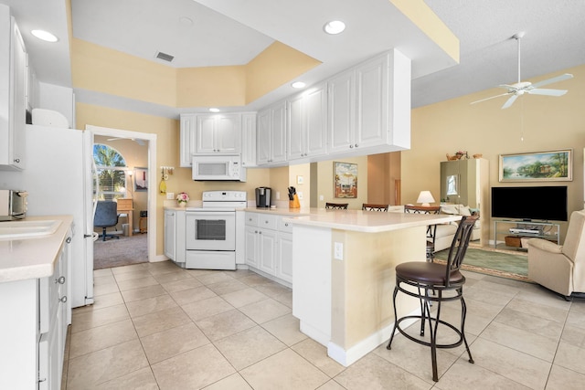 kitchen featuring a kitchen breakfast bar, white cabinets, kitchen peninsula, white appliances, and light tile patterned floors