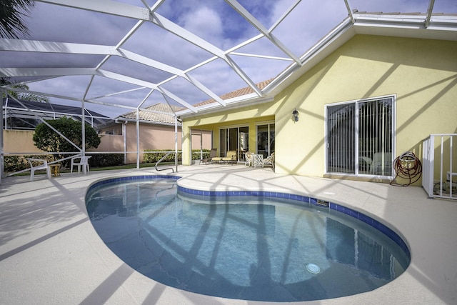 view of pool with glass enclosure and a patio area