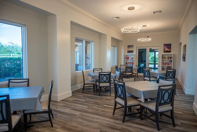 dining room featuring a notable chandelier, built in features, dark wood-type flooring, and ornamental molding