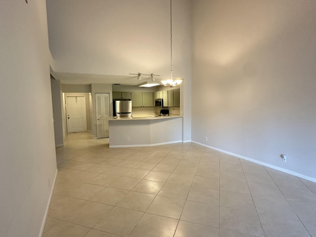 unfurnished living room with light tile patterned floors, a towering ceiling, and a chandelier