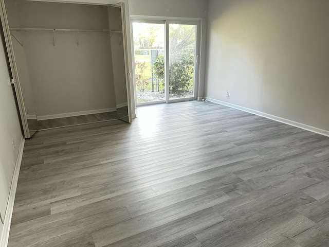 unfurnished bedroom with wood-type flooring, a closet, and access to outside