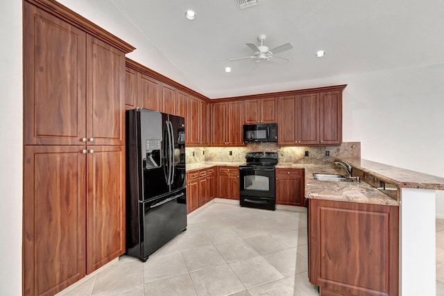 kitchen with a peninsula, a sink, decorative backsplash, light stone countertops, and black appliances