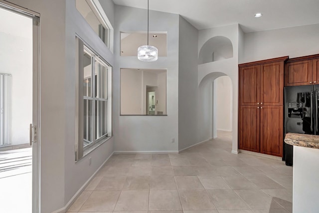 interior space featuring high vaulted ceiling, arched walkways, baseboards, and light tile patterned floors