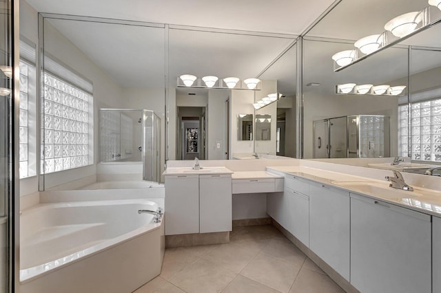 full bath featuring a garden tub, a sink, a shower stall, and tile patterned floors