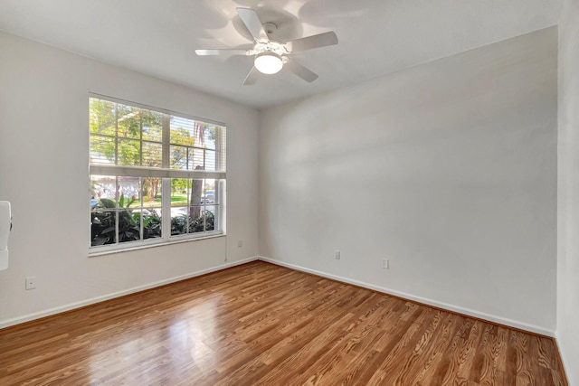 empty room with a ceiling fan, baseboards, and wood finished floors