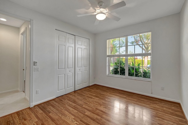 unfurnished bedroom with a ceiling fan, a closet, baseboards, and wood finished floors