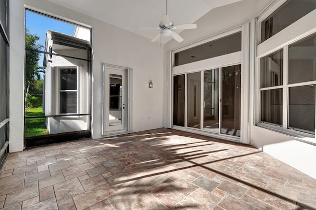 unfurnished sunroom with lofted ceiling, a wealth of natural light, and a ceiling fan