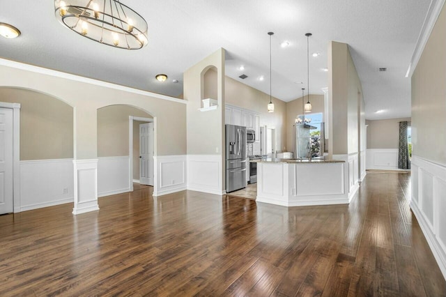 interior space with white cabinets, dark wood-type flooring, appliances with stainless steel finishes, and hanging light fixtures