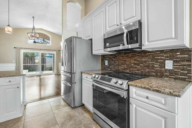 kitchen featuring decorative light fixtures, white cabinets, light tile patterned flooring, dark stone counters, and appliances with stainless steel finishes