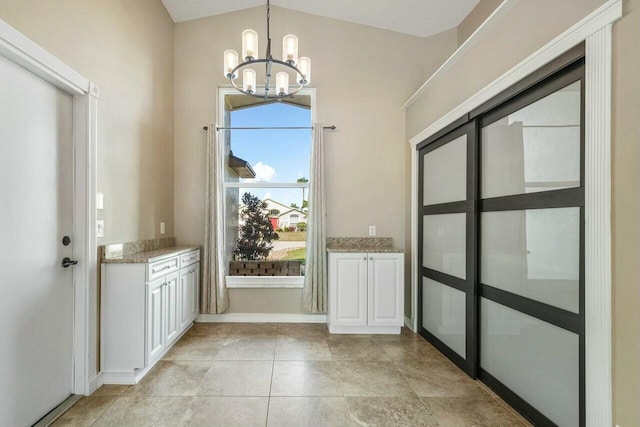 entryway featuring a wealth of natural light, vaulted ceiling, and a chandelier