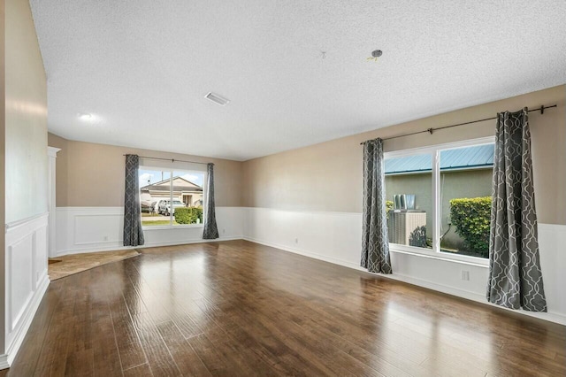 empty room with a textured ceiling and dark hardwood / wood-style flooring