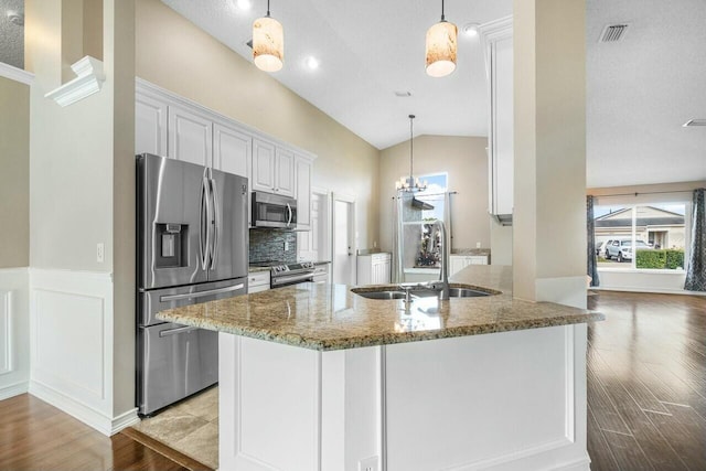 kitchen featuring stainless steel appliances, sink, white cabinetry, lofted ceiling, and stone countertops