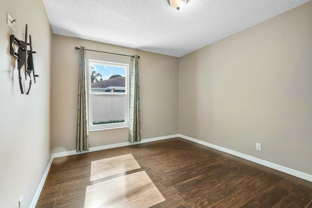 empty room featuring a textured ceiling and dark hardwood / wood-style floors