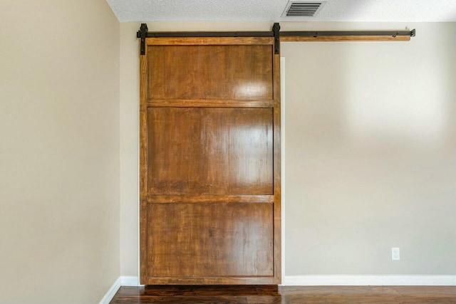 interior space featuring a textured ceiling, a barn door, and dark hardwood / wood-style flooring