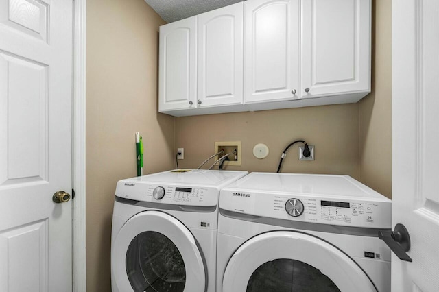 clothes washing area featuring a textured ceiling, cabinets, and separate washer and dryer