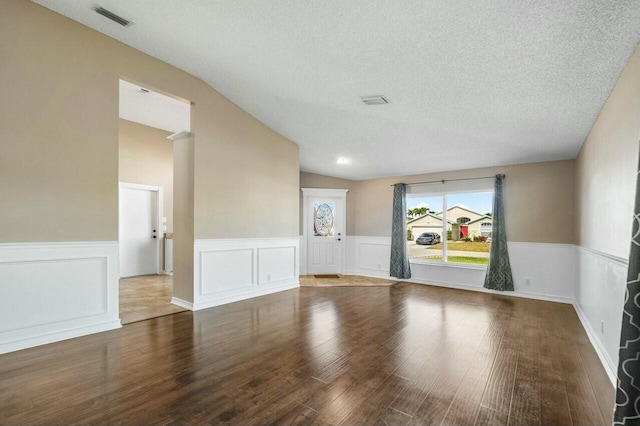 unfurnished room featuring hardwood / wood-style flooring, a textured ceiling, and vaulted ceiling