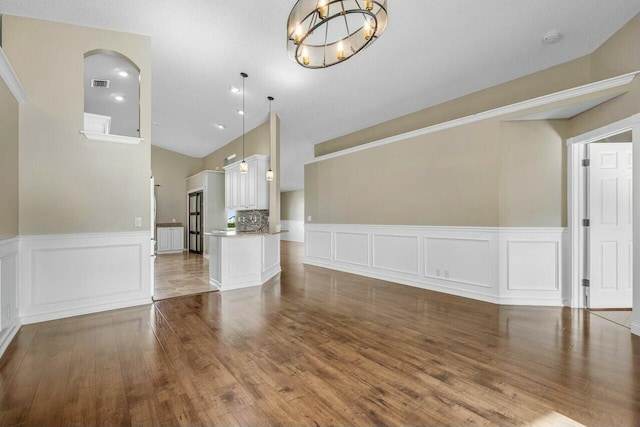 unfurnished living room featuring wood-type flooring and a notable chandelier