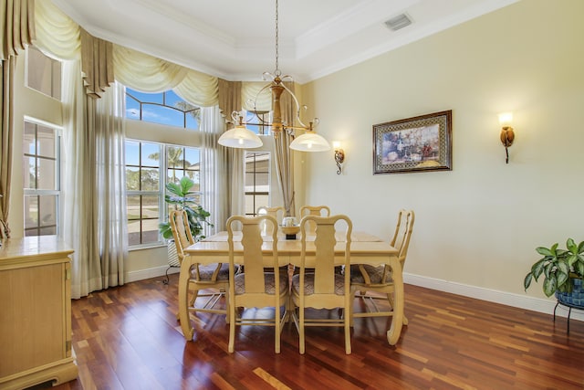 dining space with a raised ceiling, a notable chandelier, dark hardwood / wood-style flooring, and ornamental molding