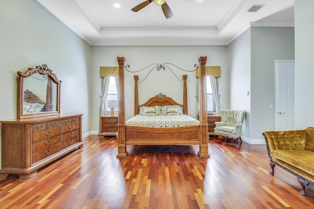 bedroom with a tray ceiling, ceiling fan, ornamental molding, and hardwood / wood-style flooring