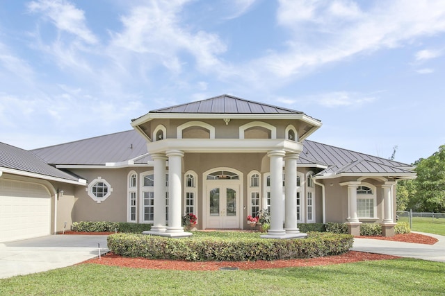 view of front of home with a garage, french doors, and a front lawn