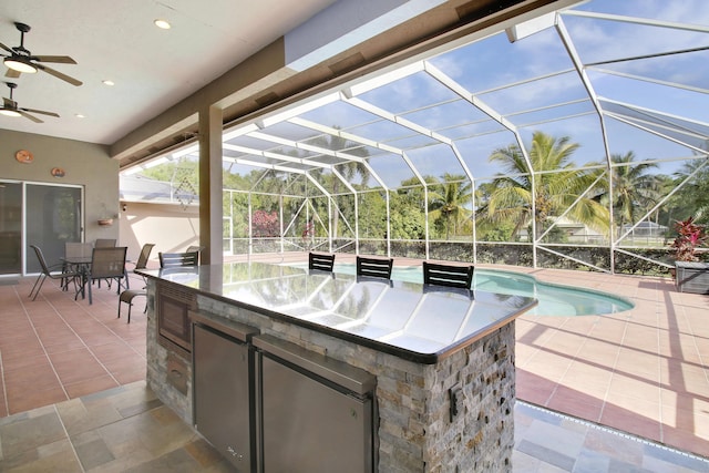 view of patio with a bar, an outdoor kitchen, and a lanai