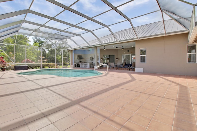 view of swimming pool with glass enclosure, ceiling fan, and a patio area