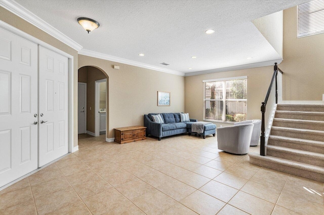 living room featuring light tile patterned floors, a textured ceiling, and ornamental molding