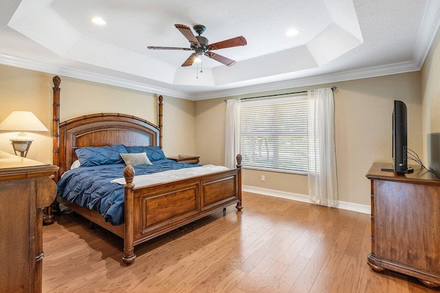 bedroom featuring ceiling fan, light wood-type flooring, crown molding, and a tray ceiling