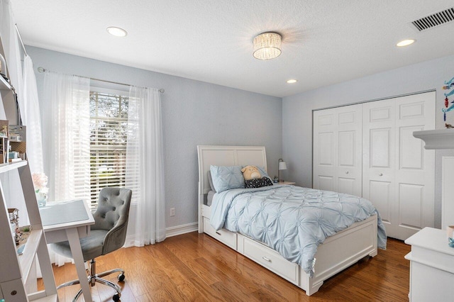 bedroom featuring wood-type flooring, a textured ceiling, and a closet