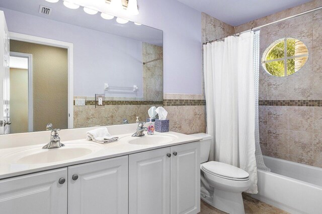 full bathroom with vanity, shower / bathtub combination with curtain, tile walls, and toilet