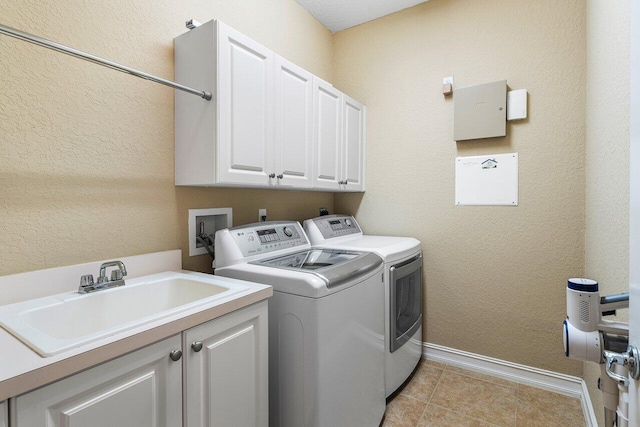 clothes washing area featuring cabinets, sink, and washing machine and dryer