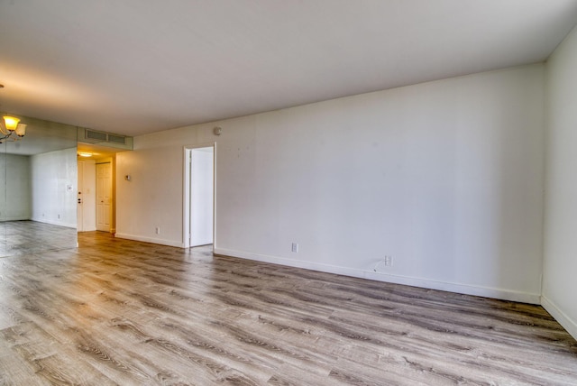 spare room with light hardwood / wood-style floors and a chandelier