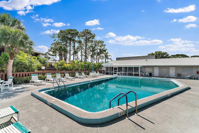 pool featuring a sunroom, a patio area, and fence