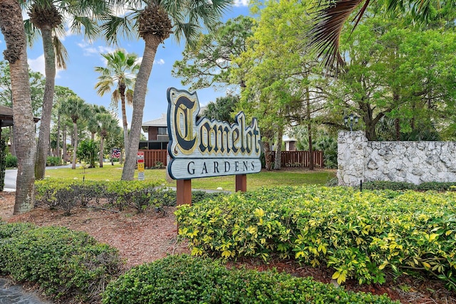 community / neighborhood sign featuring a lawn and fence