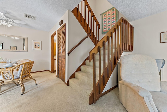 stairs with carpet floors, baseboards, visible vents, and a textured ceiling