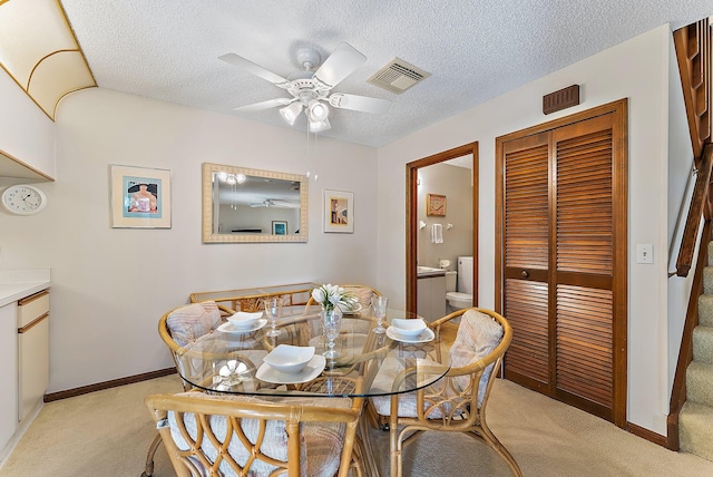 dining area featuring visible vents, stairway, a ceiling fan, light carpet, and a textured ceiling