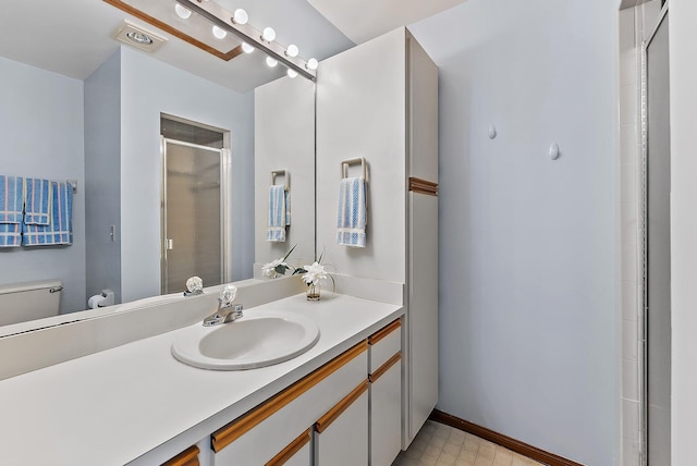 full bath with toilet, a shower stall, baseboards, and vanity