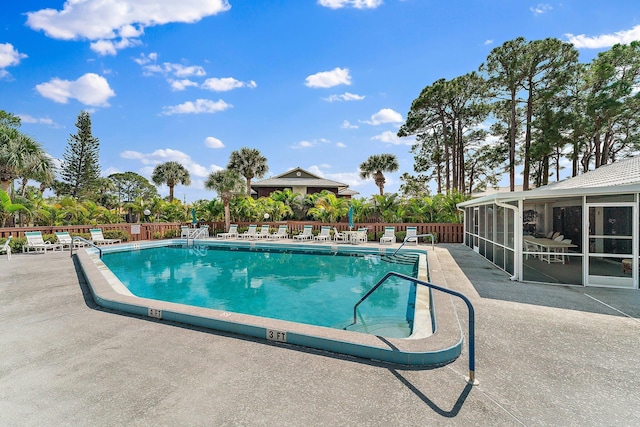 community pool with a patio, fence, and a sunroom