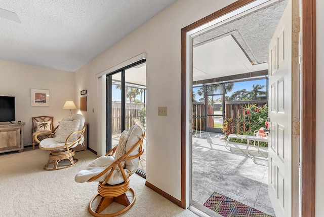 interior space featuring a textured ceiling, carpet floors, a sunroom, and baseboards