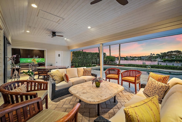 patio terrace at dusk featuring an outdoor living space, a water view, and ceiling fan