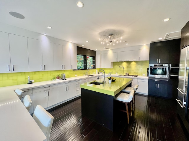 kitchen featuring light countertops, white cabinets, a kitchen island with sink, and a sink