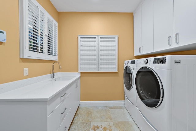 clothes washing area featuring sink, washing machine and clothes dryer, and cabinets