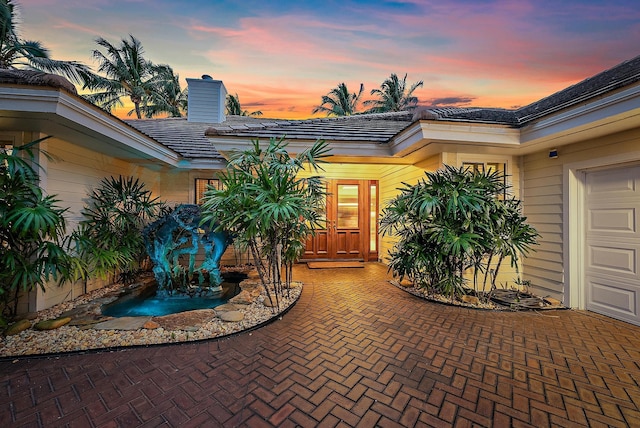 exterior entry at dusk featuring a garage